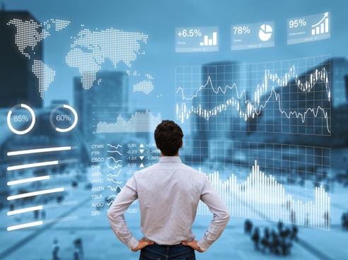 Business man standing in front of a screen analyzing numerous graphs, maps, and chart
