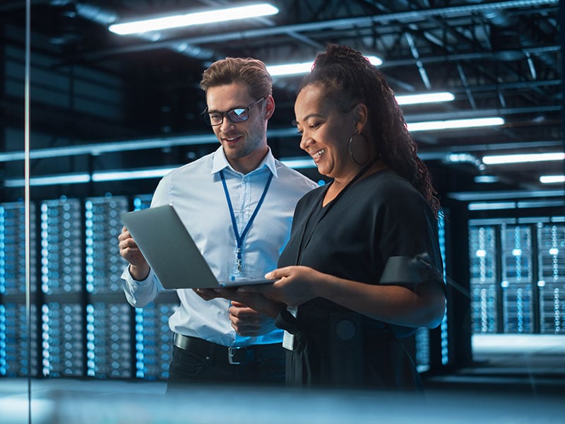 Senior CEO Talking to Young Confident Manager while Using Computer in Modern Office