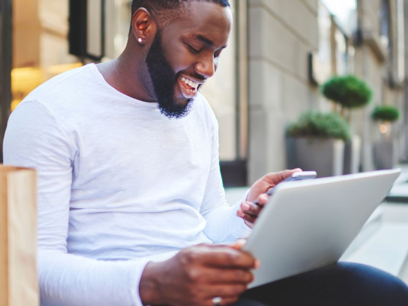 Cheerful-afro-american-hipster-guy-happy-about-getting-discount-on-email-for-shopping-in-web-store