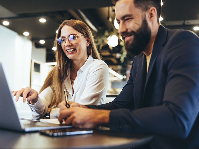Cheerful-businesspeople-using-a-laptop-in-an-office