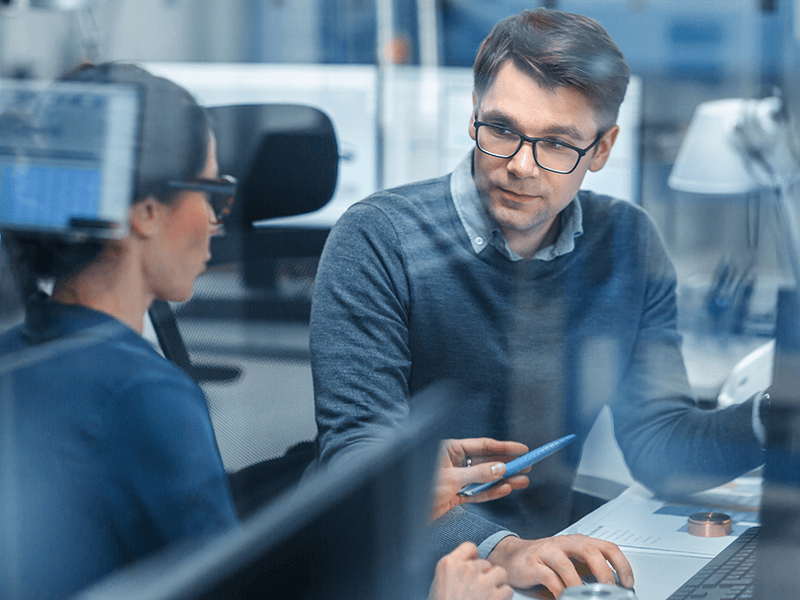 Female-Project-Supervisor-Talks-to-a-Male-Industrial-Engineer-who-Works-on-Personal-Computer